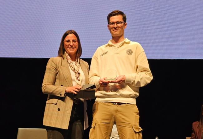 Sergio Viamonte, enfermero del CS Cascante, recibe el segundo premio a la Mejor Comunicación Oral de manos de la profesora Nuria Esandi por el estudio ""Intervención comunitaria de enfermería: Programa Vivifrail para la prevención de fragilidad y caídas en mayores de 70 años"